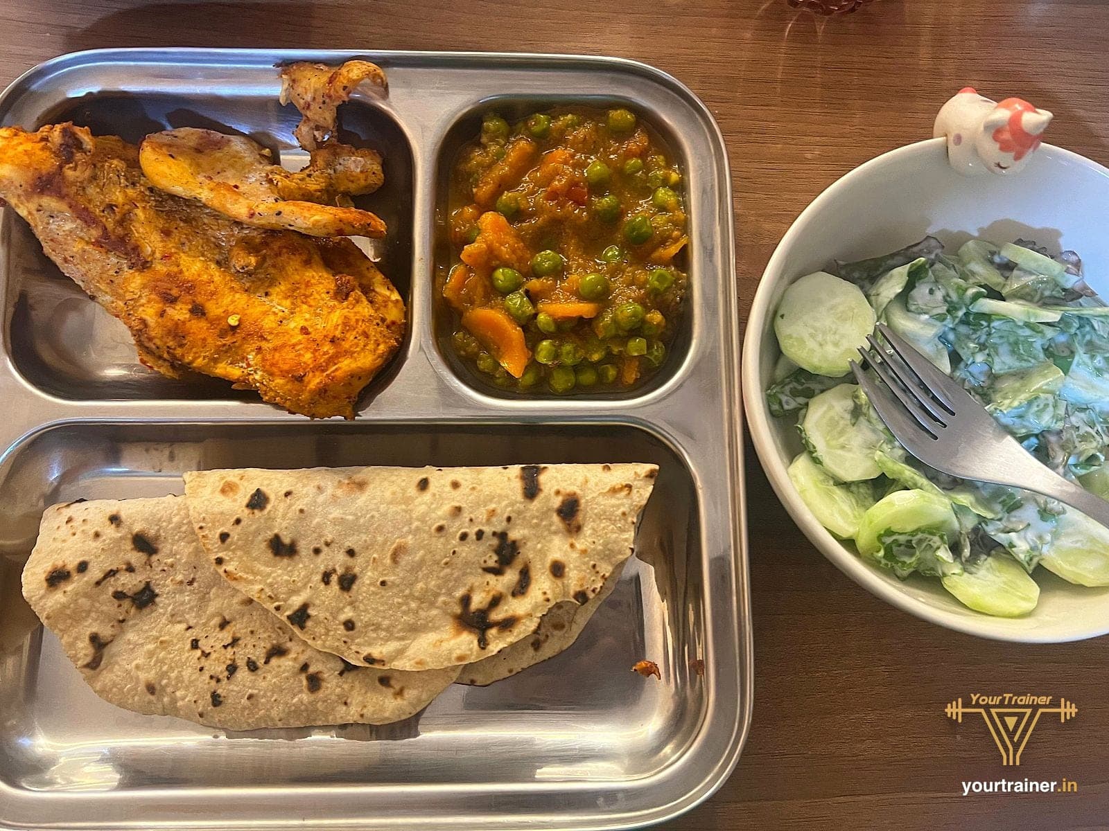 Chicken with roti, peas and carrot on a tray with raita