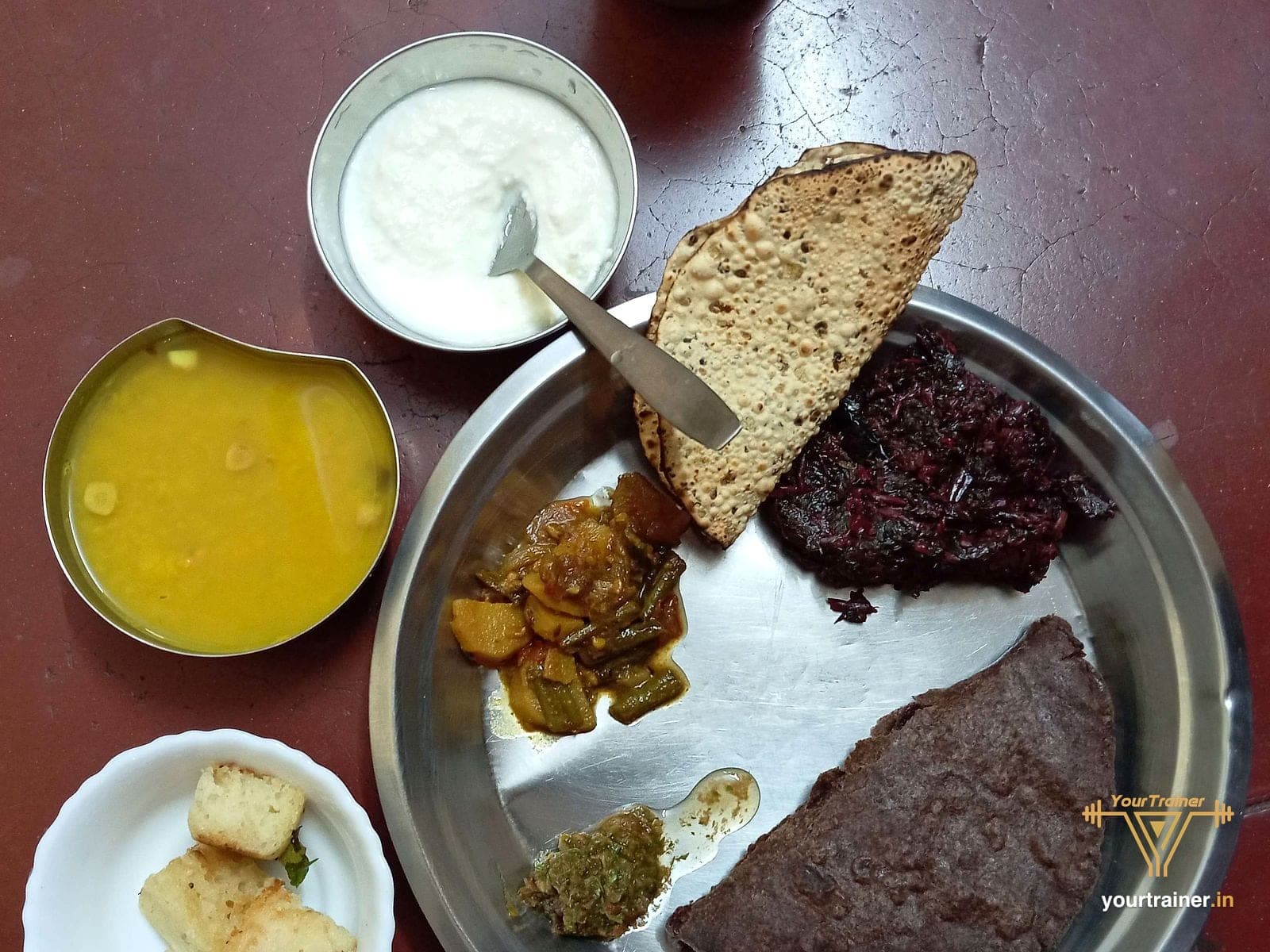 Steel thali with ragi roti, dal, beetroot, a vegetable sabzi and curd