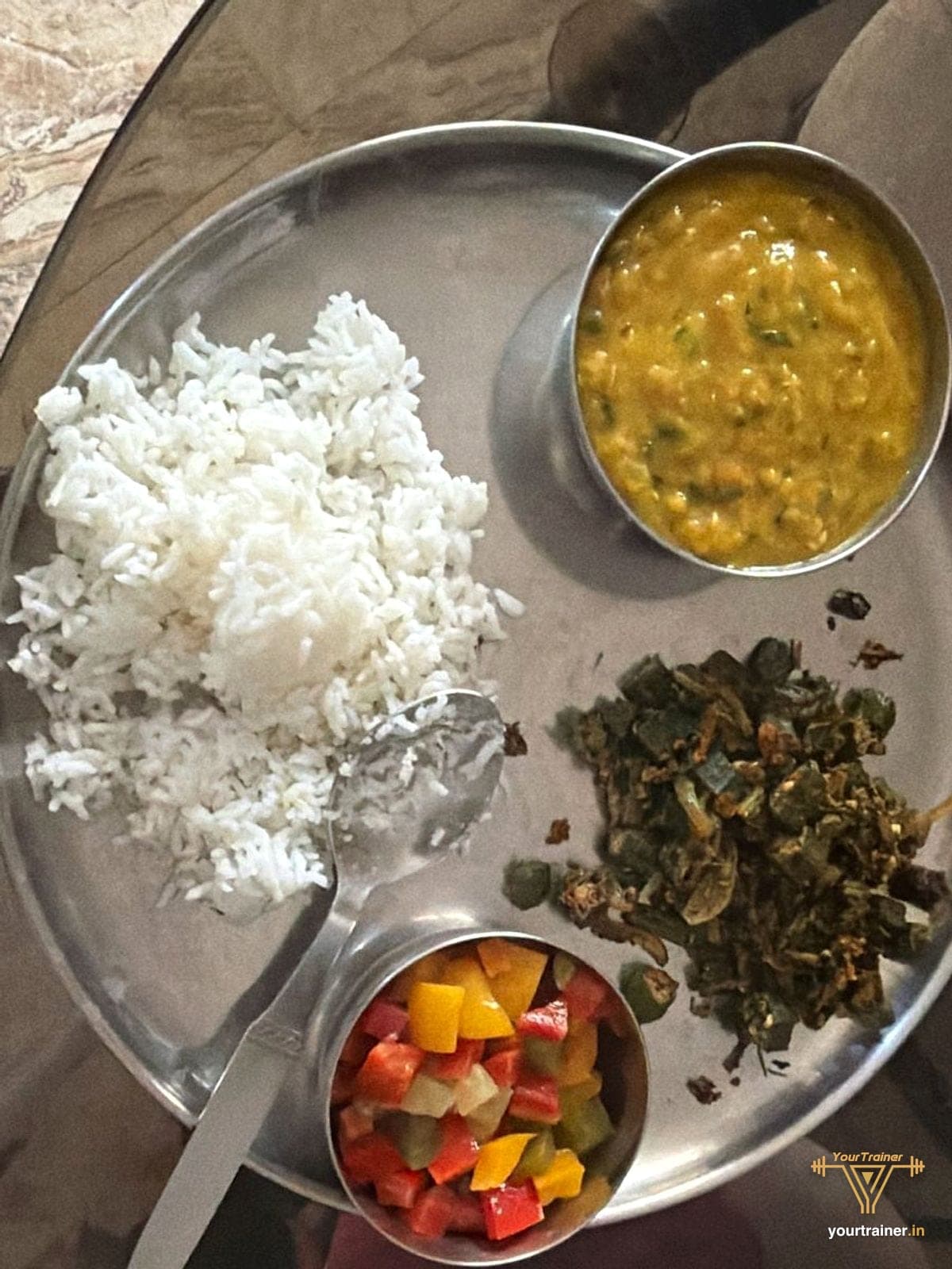 Steel thali with rice, dal, bhindi and a salad