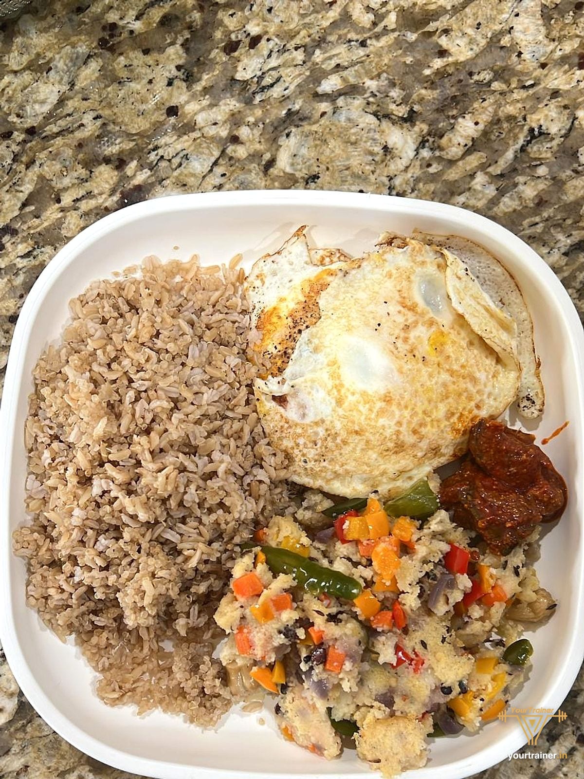 Plate of brown rice, two fried eggs, a vegetable scramble and achar