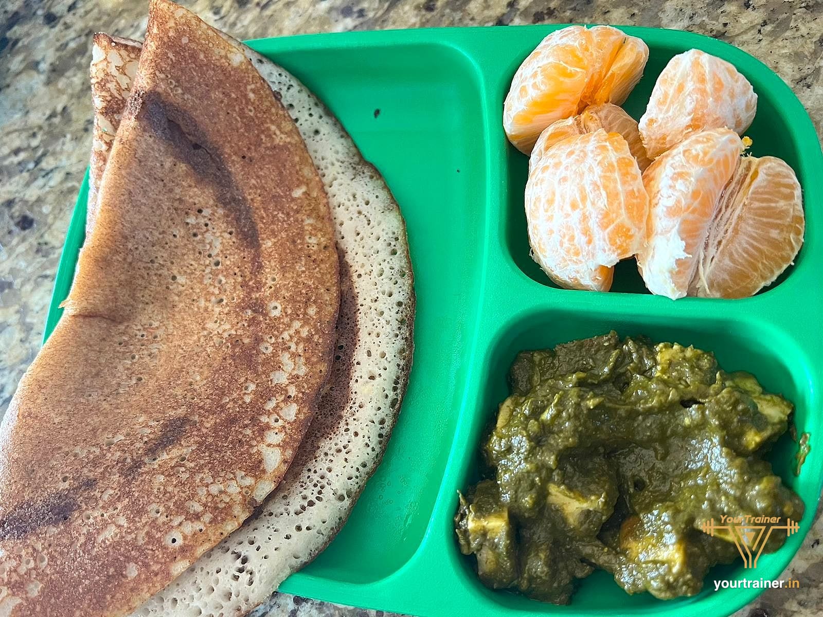 Tray with a dosa, palak paneer and orange segments