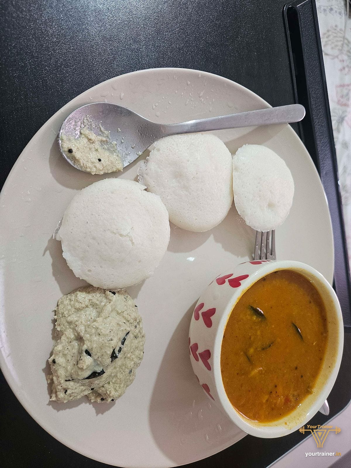 Idli with sambar and coconut chutney on a white plate