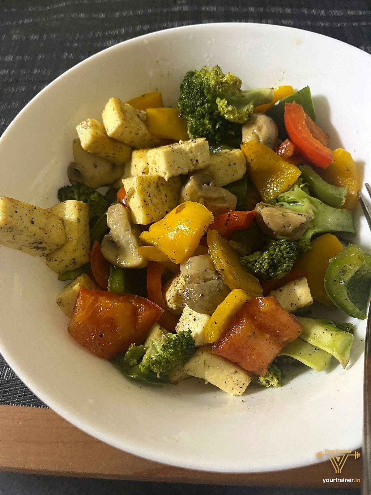 Bowl of paneer cubes stir-fried with broccoli, bell peppers and mushrooms