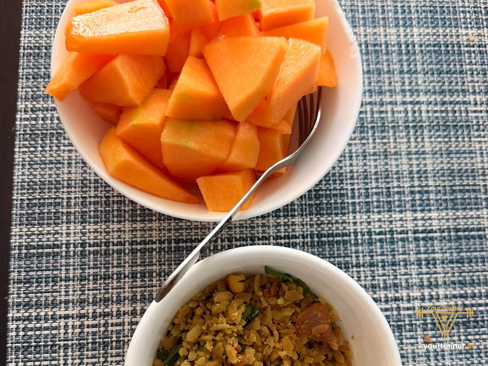 A bowl of papaya pieces beside a bowl of poha