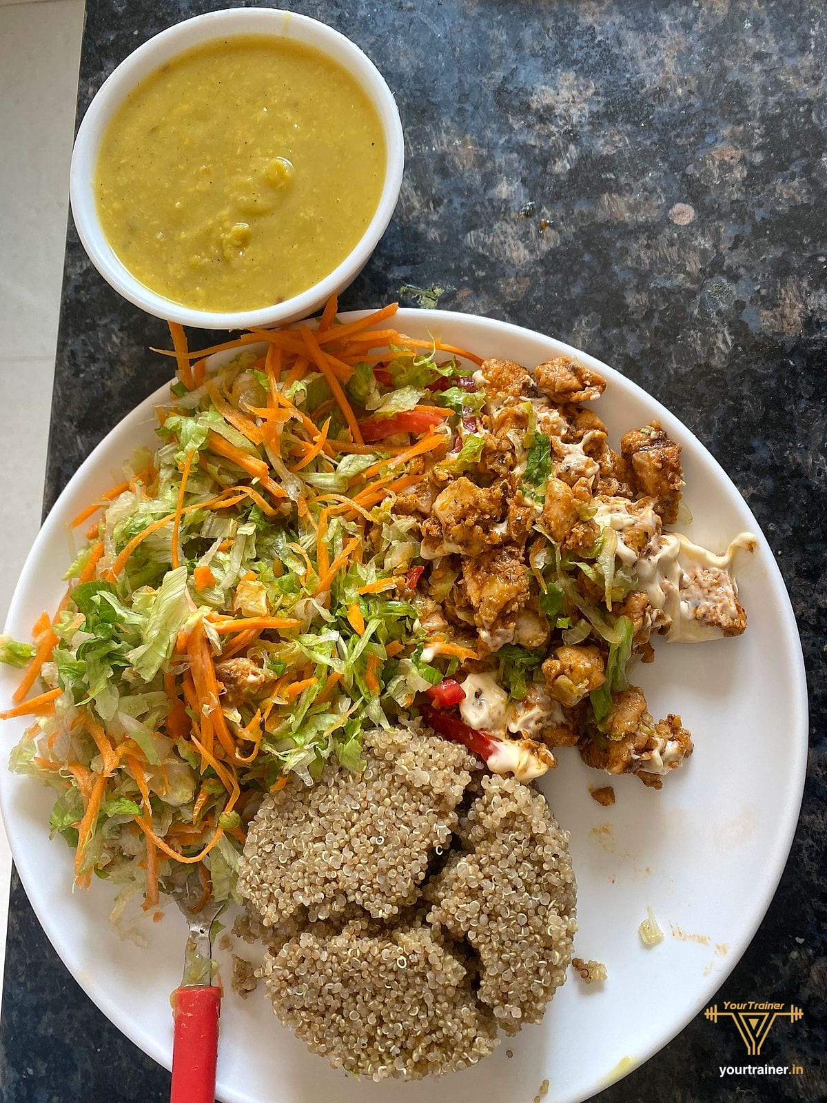 Plate of quinoa, shredded carrot and cabbage salad and bhurji, with a bowl of dal